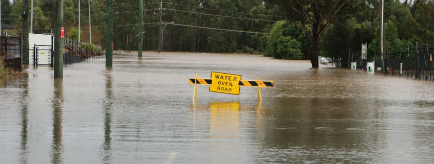 Überflutete Straße bei Windsor in Australien mit einer Absperrung im Wasser