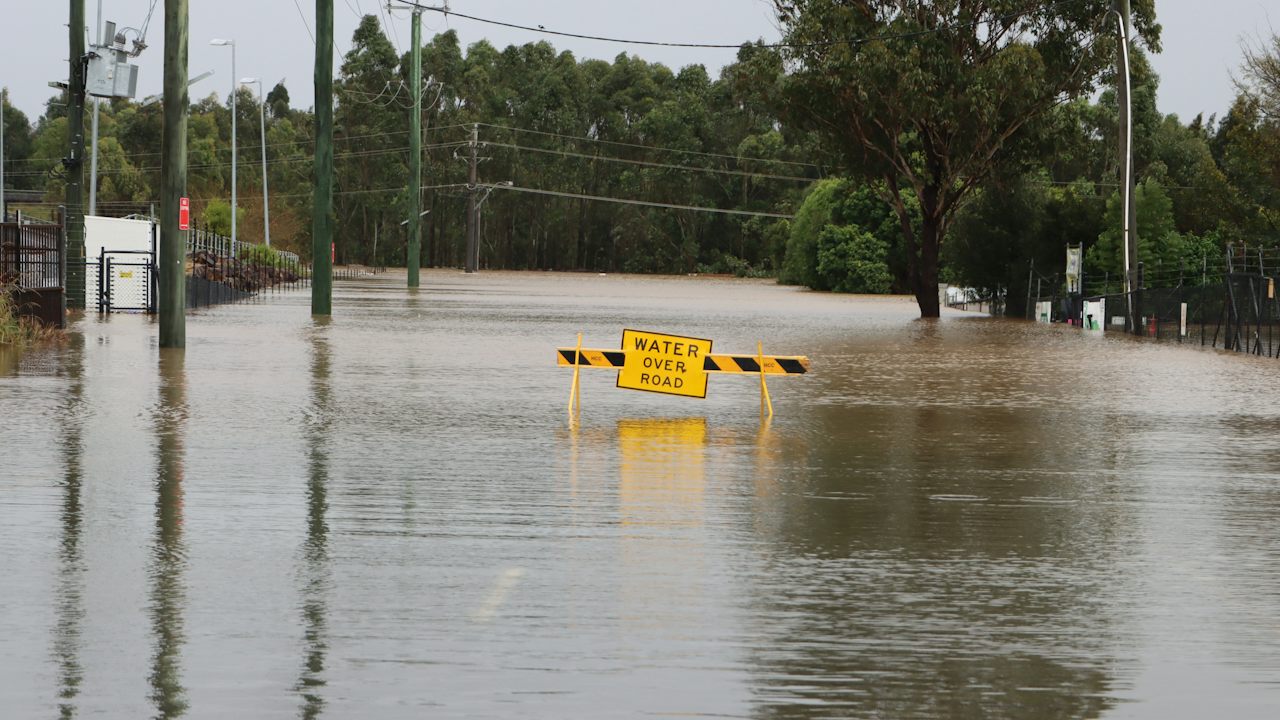Überflutete Straße bei Windsor in Australien mit einer Absperrung im Wasser