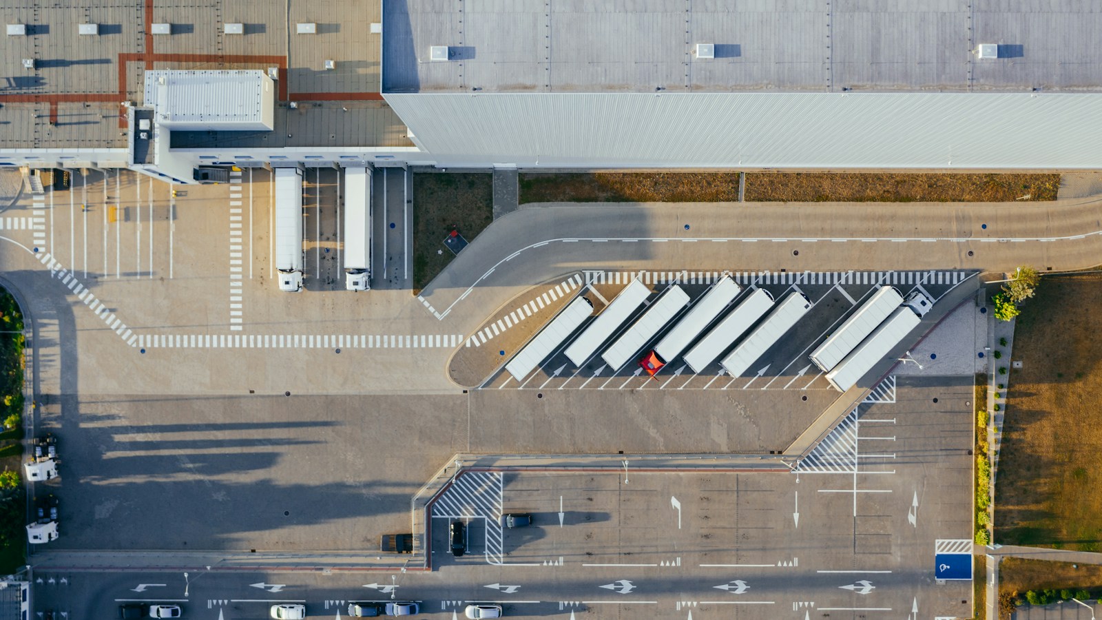 Luftaufnahme eines Logistikhofs mit Lkw, Aufliegern, Stellflächen und Verladerampen.